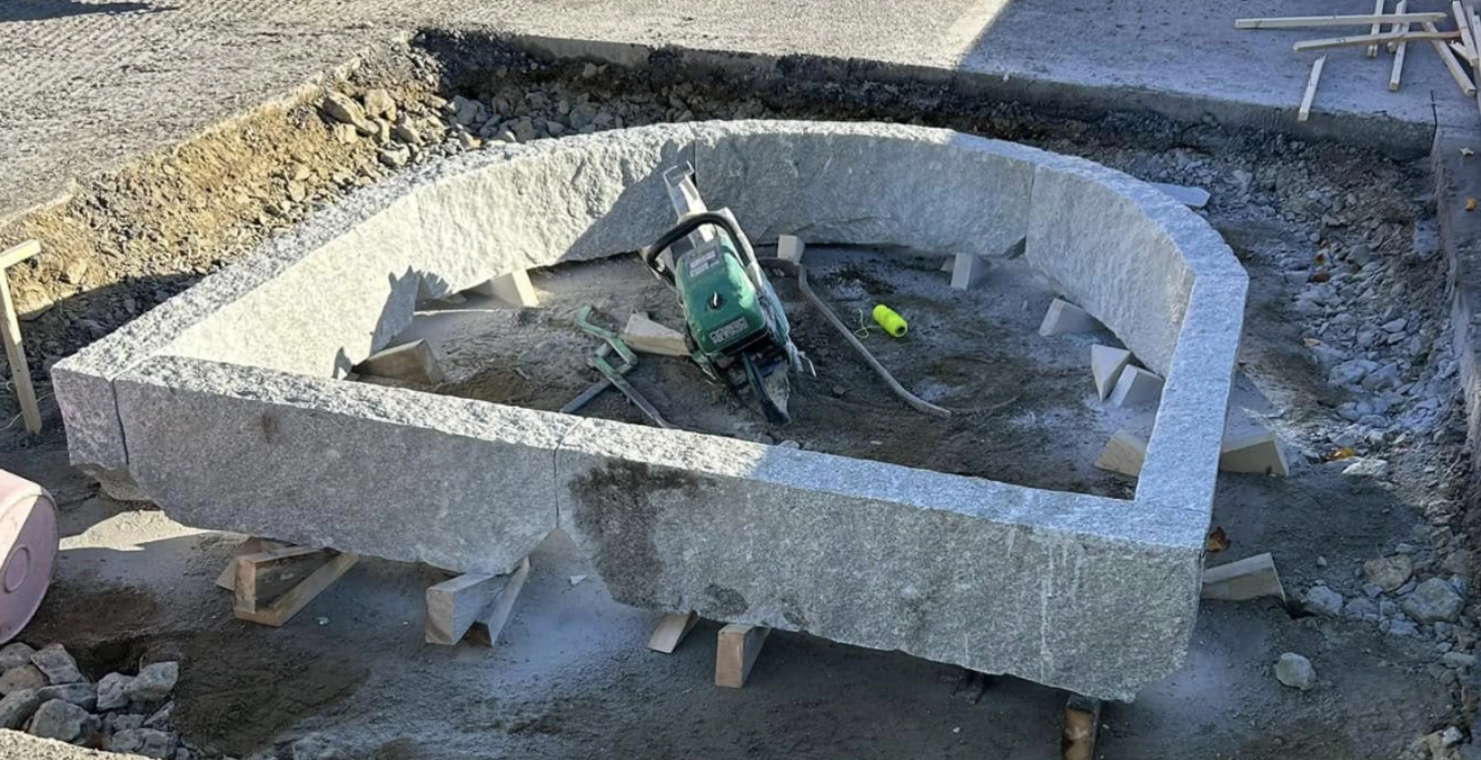 Murning och anläggning av en cirkulär kantsten i granit på en byggarbetsplats.