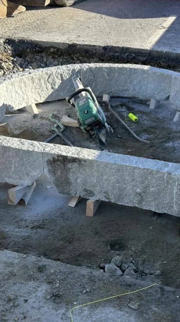 Närbild på justering och kapning av grov kantsten eller granitblock inför en stensättning.